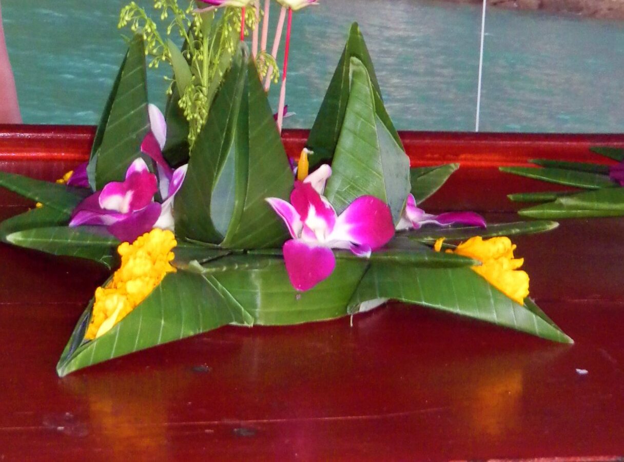 The Grand Palace lit across the Chao Phraya after dark — the river Loy Krathong happens on